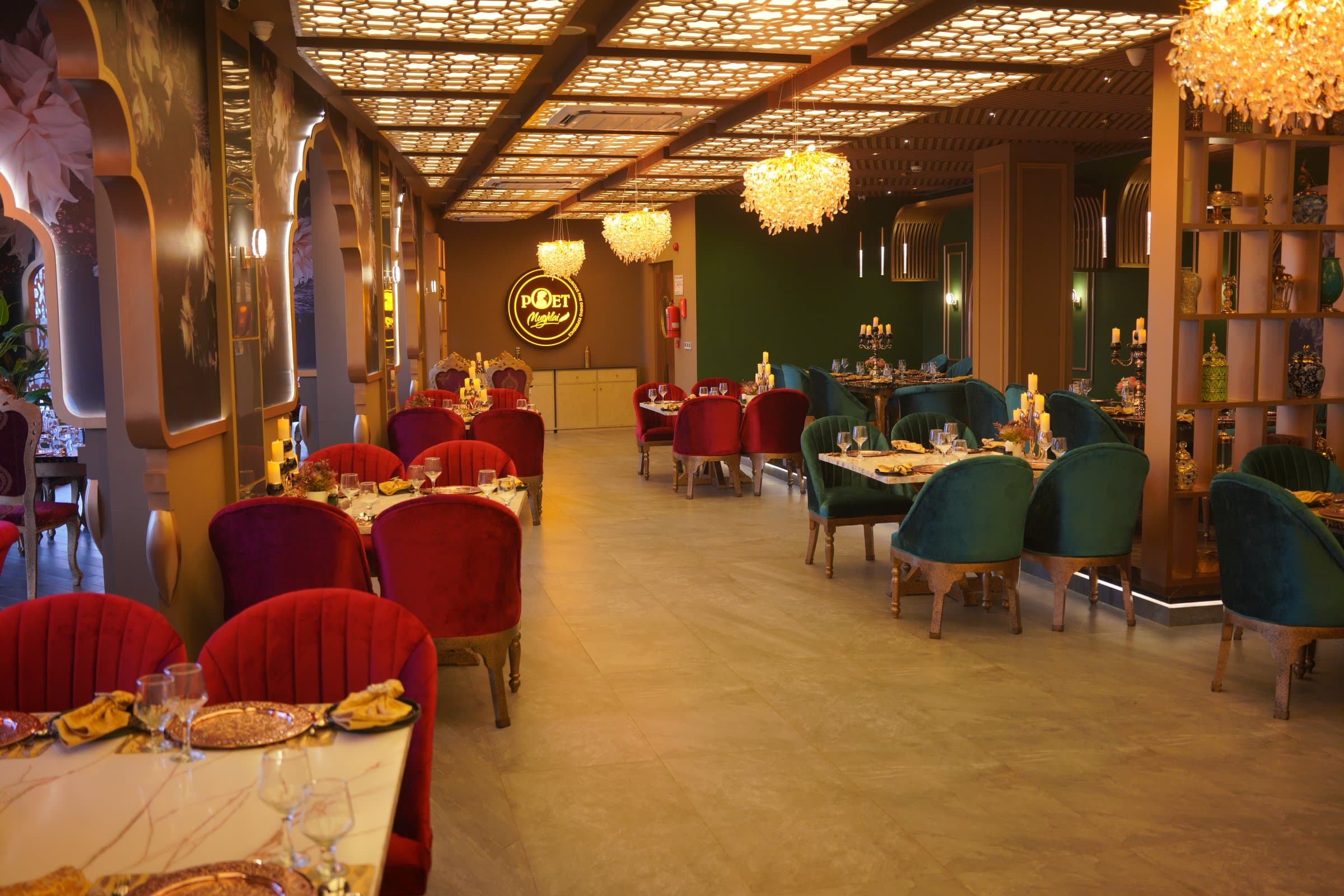 The main dining room at Poet Mughlai with crystal chandeliers, Mughal arches and emerald velvet seating